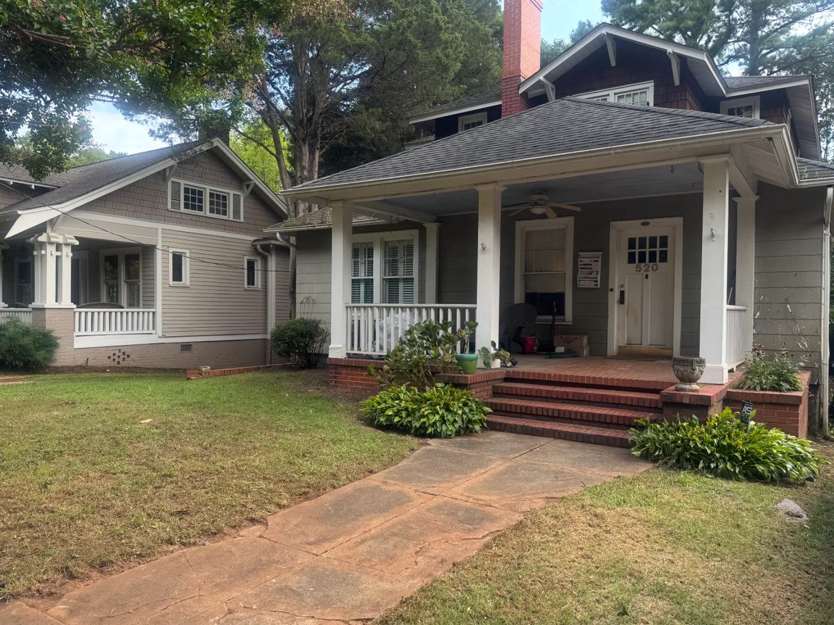 The same front yard after bed cleanup and shrub trimming, with tidy beds and the porch in full view