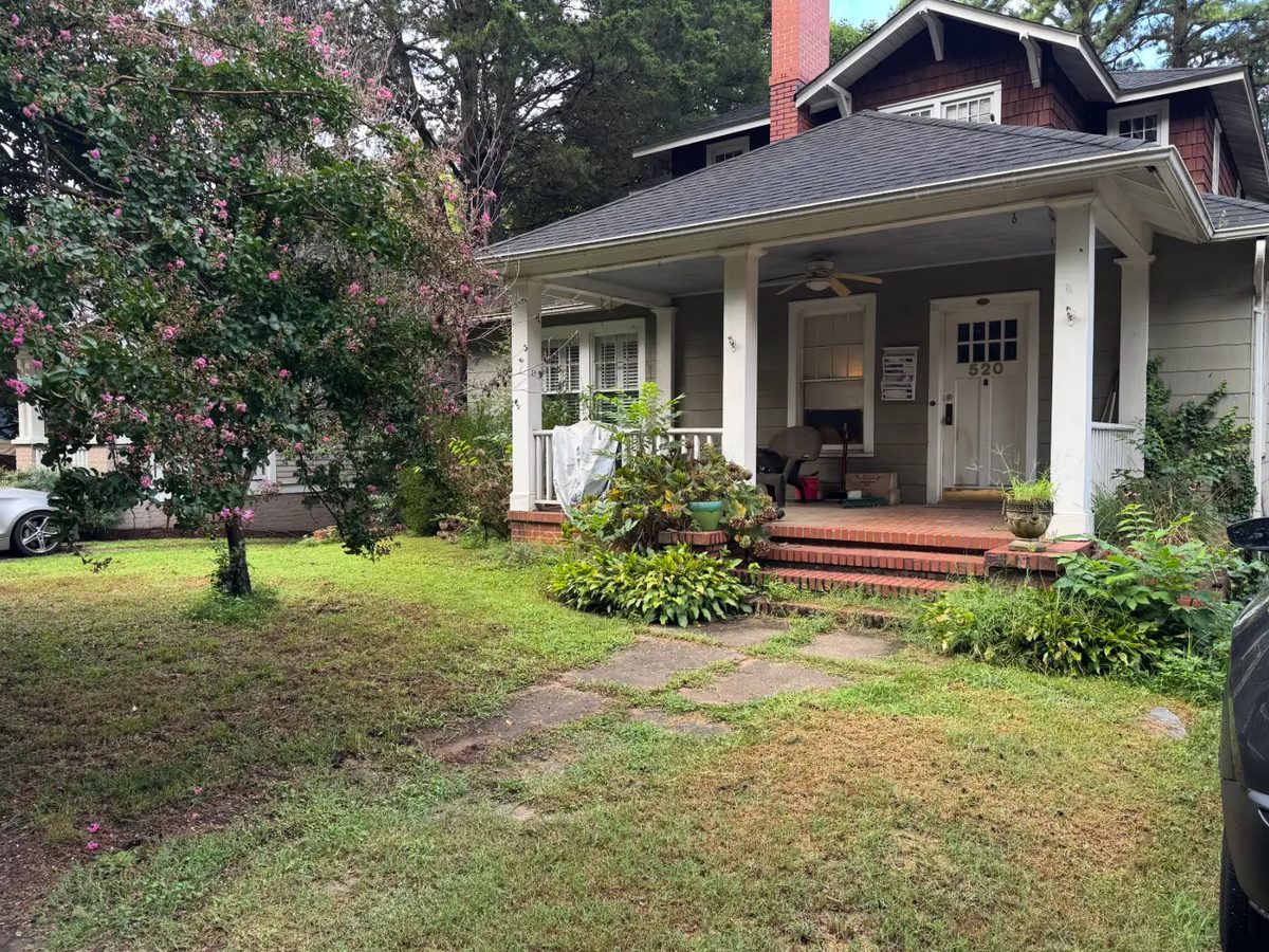 Craftsman bungalow front yard with overgrown beds and shaggy shrubs crowding the porch before cleanup