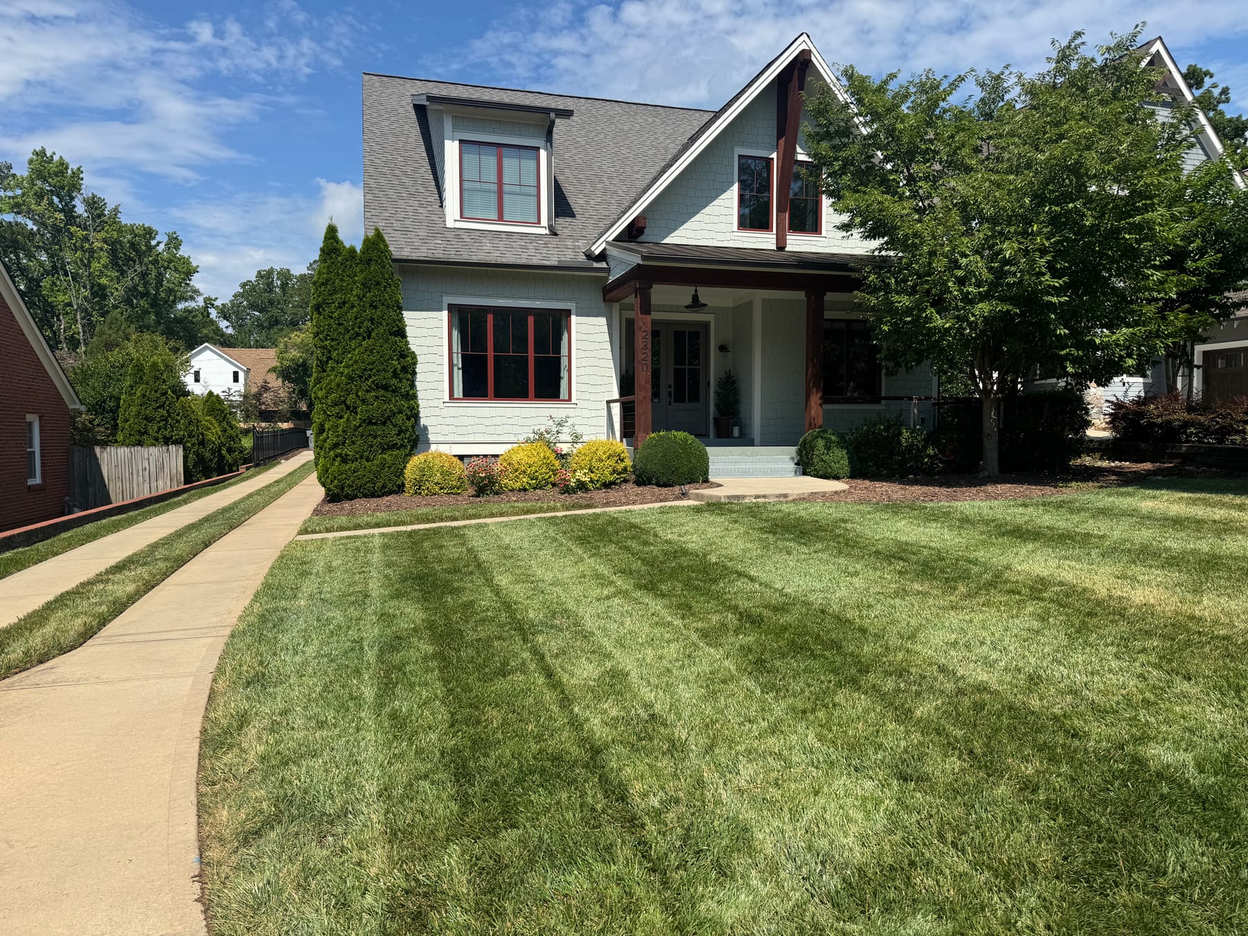 The same front lawn after mowing and edging, with clean stripes and crisp borders