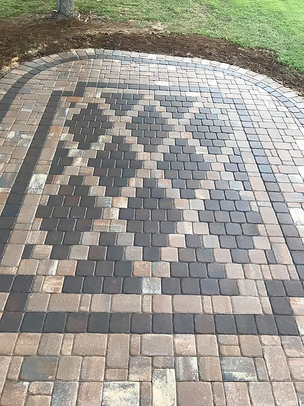 Rounded paver patio with a dark diamond mosaic inlay and a double border course, freshly installed